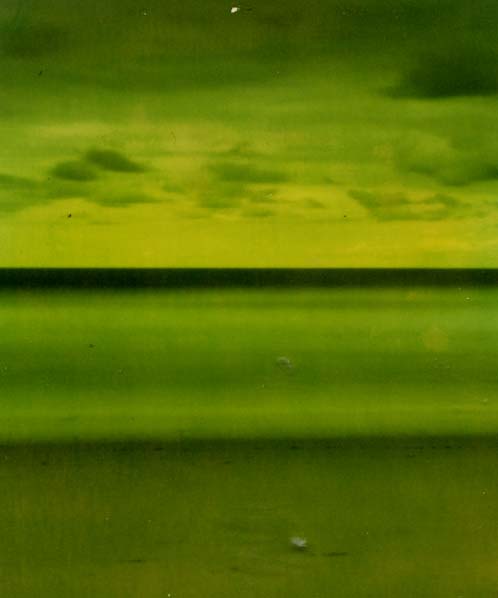 Green-toned pinhole photograph of a beach, sea and cloudy sky.