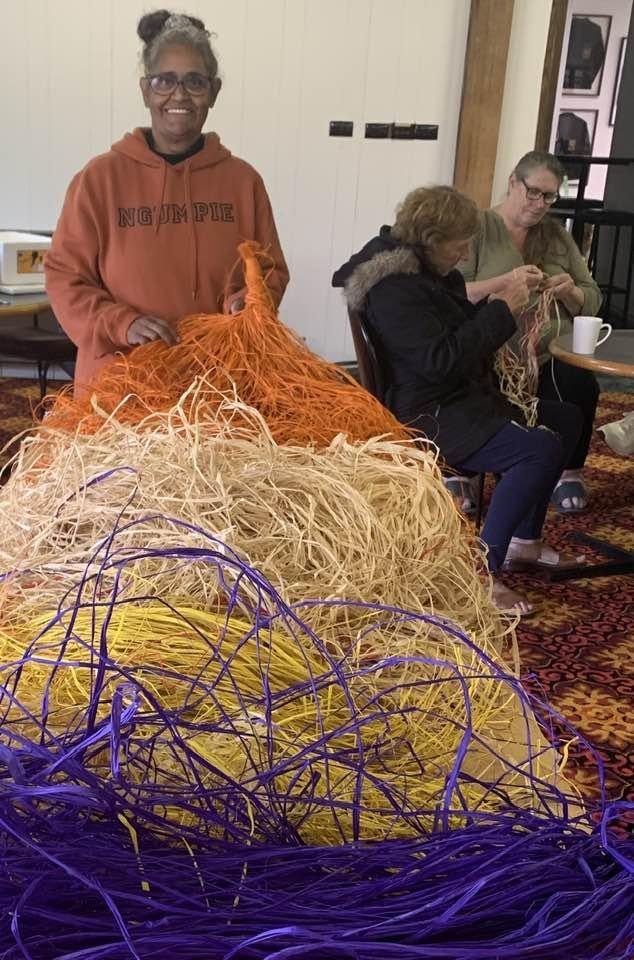 Workshop participants weaving with bundles of natural and purple fibre.